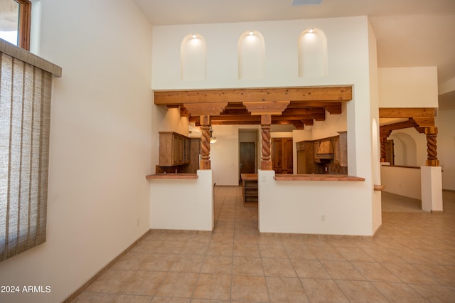 kitchen featuring beamed ceiling, kitchen peninsula, and light tile floors