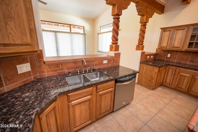 kitchen featuring dark stone countertops, stainless steel dishwasher, backsplash, sink, and light tile flooring