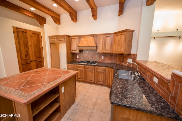 kitchen with kitchen peninsula, tasteful backsplash, premium range hood, stainless steel gas cooktop, and sink