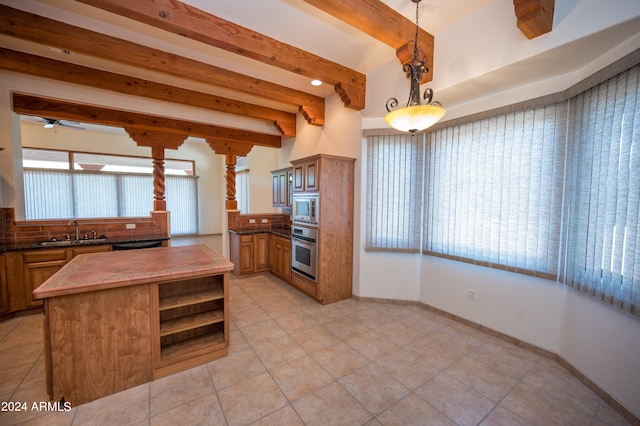 kitchen with light tile flooring, beamed ceiling, appliances with stainless steel finishes, sink, and pendant lighting
