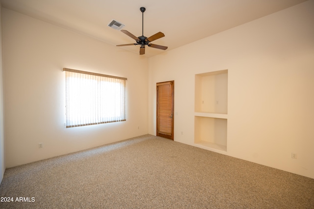 carpeted empty room with built in features and ceiling fan