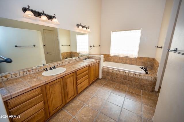 bathroom featuring tile flooring, tiled bath, and double vanity