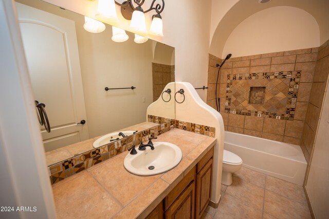 full bathroom with tiled shower / bath, tile flooring, oversized vanity, and toilet