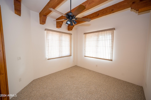 empty room featuring beam ceiling, carpet, and ceiling fan