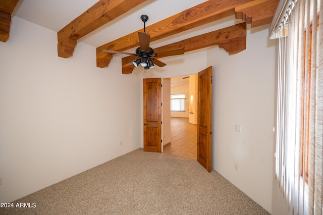 carpeted empty room featuring beam ceiling and ceiling fan