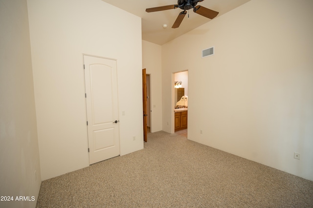 unfurnished bedroom featuring a towering ceiling, ensuite bath, ceiling fan, and carpet floors