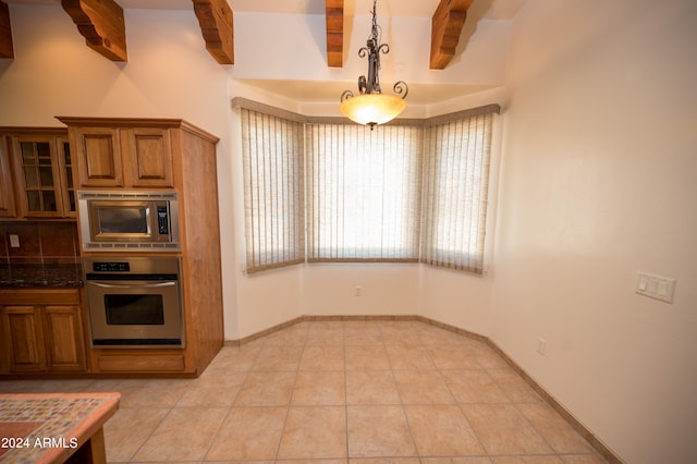 kitchen featuring hanging light fixtures, beam ceiling, light tile floors, and appliances with stainless steel finishes