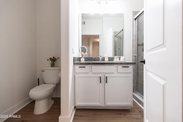 bathroom featuring toilet, vanity, wood-type flooring, and a shower with door