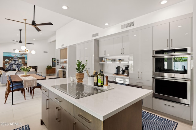 5438 E Lupine Ave, Scottsdale, AZ 85254 - kitchen with double oven, black electric stovetop, a ceiling fan, a center island, and hanging light fixtures