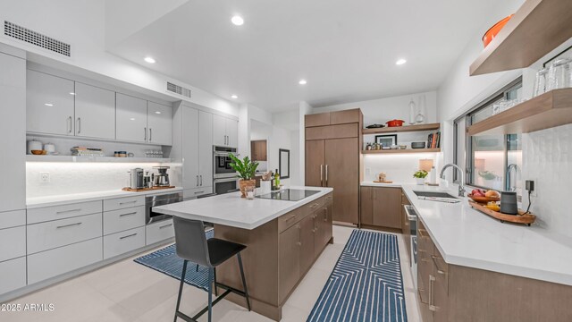 5438 E Lupine Ave, Scottsdale, AZ 85254 - kitchen featuring open shelves, a sink, a kitchen island, black electric cooktop, and a breakfast bar