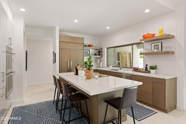5438 E Lupine Ave, Scottsdale, AZ 85254 - kitchen featuring open shelves, a breakfast bar area, appliances with stainless steel finishes, light countertops, and a sink
