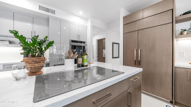 5438 E Lupine Ave, Scottsdale, AZ 85254 - kitchen with black electric cooktop, oven, modern cabinets, light stone counters, and recessed lighting