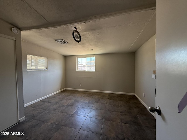 spare room with visible vents, a textured ceiling, and baseboards