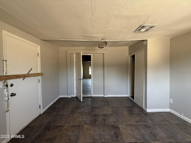 unfurnished bedroom featuring a textured ceiling, a closet, visible vents, and baseboards