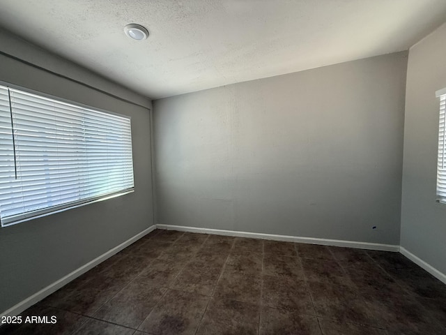 empty room featuring baseboards and a textured ceiling