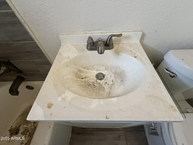 details featuring a textured wall, vanity, and toilet