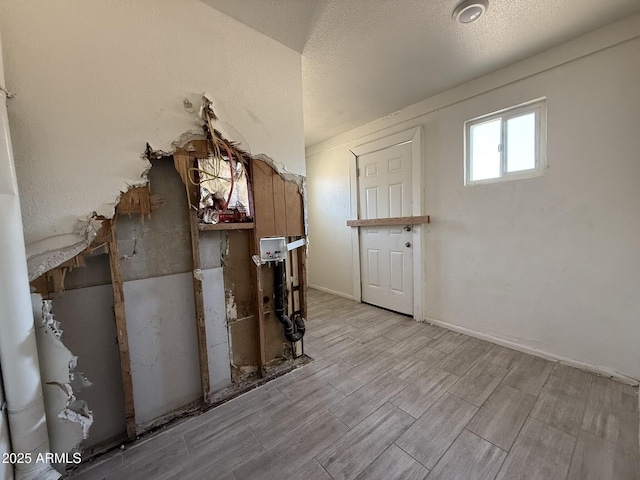 interior space with a textured ceiling, wood finish floors, and baseboards