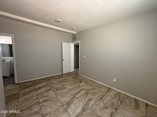 unfurnished bedroom featuring visible vents, a textured ceiling, and baseboards