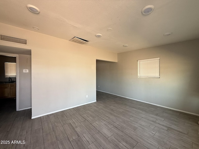 unfurnished room featuring baseboards, a sink, visible vents, and wood tiled floor