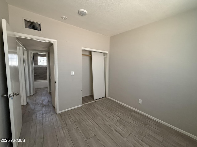 unfurnished bedroom with baseboards, wood tiled floor, visible vents, and a closet