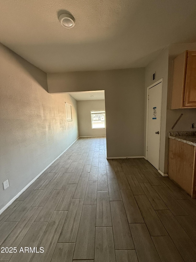 interior space featuring baseboards, a textured ceiling, and wood finish floors