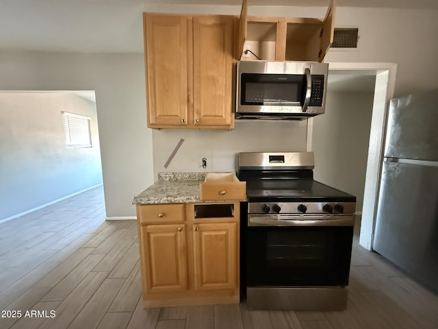 kitchen featuring wood tiled floor, light brown cabinets, baseboards, and stainless steel appliances