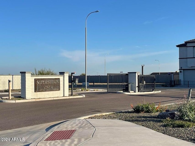 view of street featuring street lights, curbs, sidewalks, and a gated entry