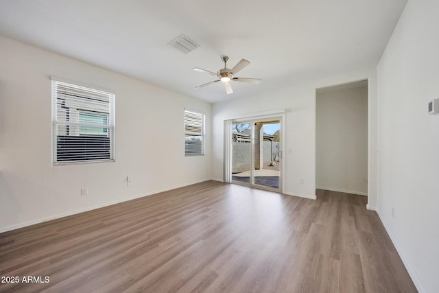 spare room featuring ceiling fan, light wood-type flooring, visible vents, and baseboards