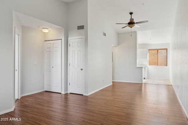 unfurnished living room featuring a ceiling fan, dark wood-style flooring, visible vents, and baseboards