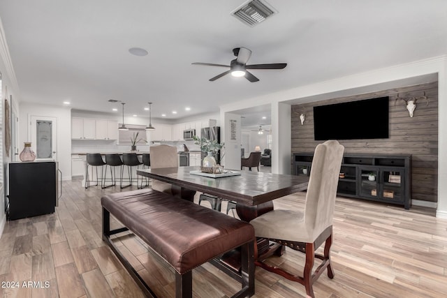 dining room featuring ceiling fan, a large fireplace, and light wood-type flooring