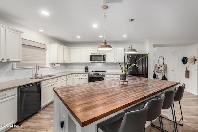 kitchen featuring pendant lighting, a center island, butcher block counters, and stainless steel appliances