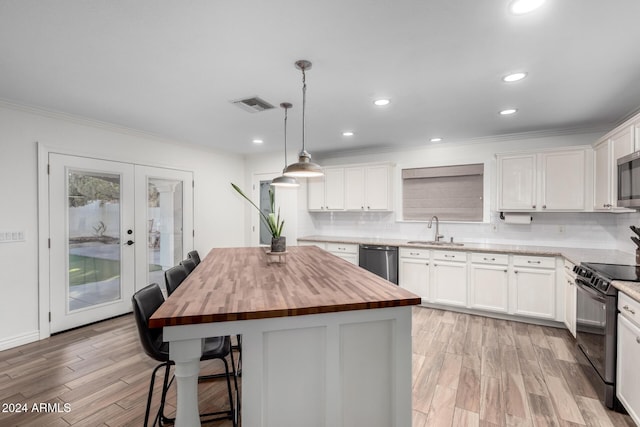 kitchen featuring decorative light fixtures, a center island, white cabinetry, and appliances with stainless steel finishes