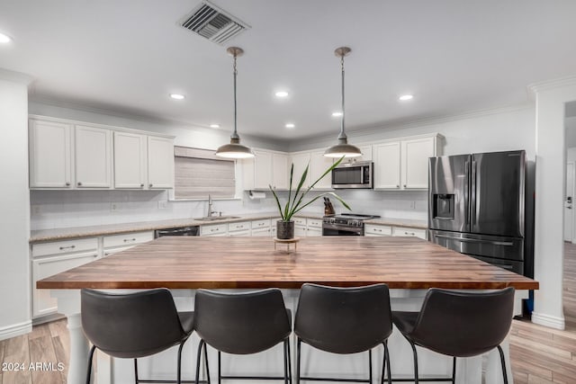 kitchen featuring wood counters, a center island, white cabinets, sink, and appliances with stainless steel finishes