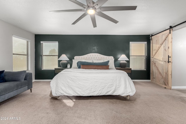 carpeted bedroom featuring a barn door and ceiling fan