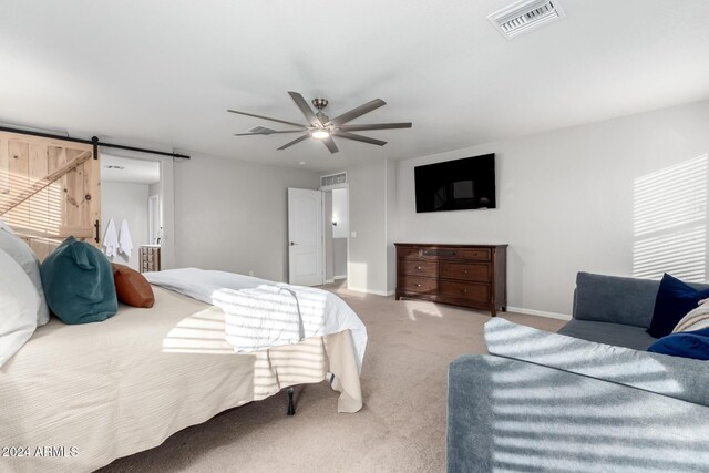 carpeted bedroom featuring a barn door and ceiling fan