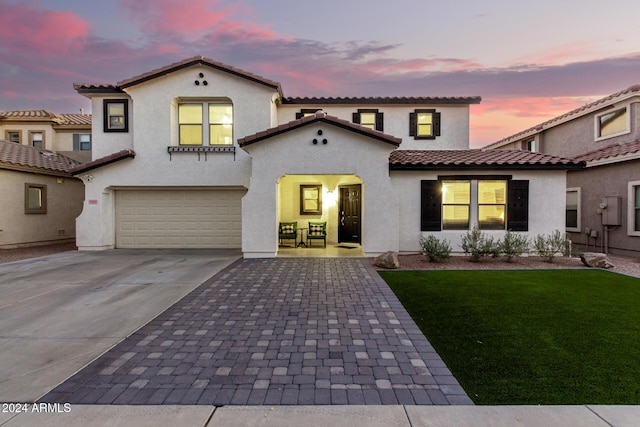 mediterranean / spanish house with a garage and a lawn