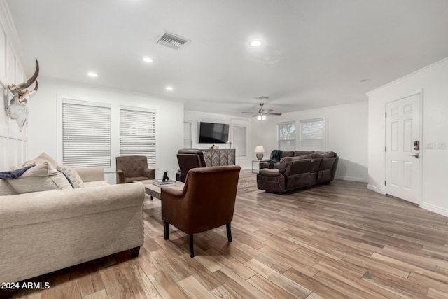 living room with ceiling fan, ornamental molding, and light hardwood / wood-style flooring