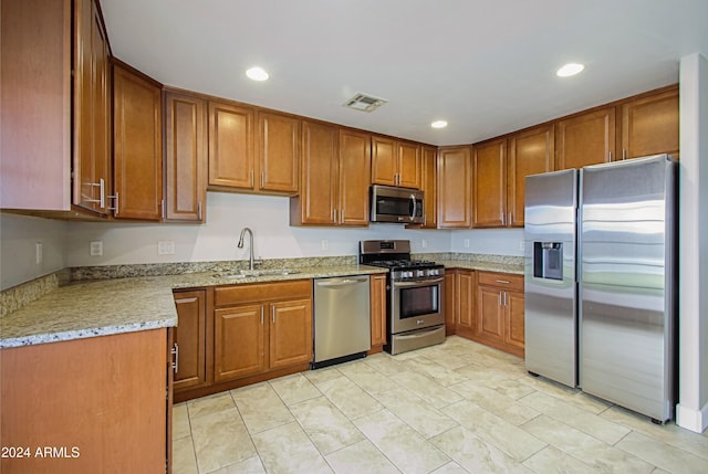 6120 W Keim Dr, Glendale, AZ 85301 - kitchen featuring light stone countertops, brown cabinetry, visible vents, appliances with stainless steel finishes, and a sink
