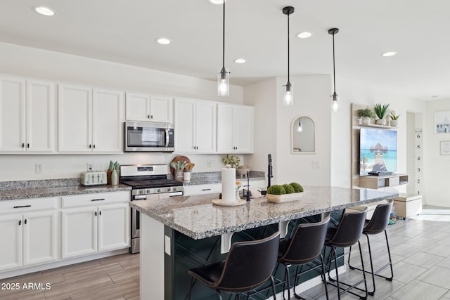 kitchen featuring a center island with sink, white cabinets, and stainless steel appliances