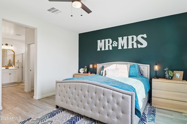 bedroom with ensuite bathroom, light hardwood / wood-style flooring, ceiling fan, and sink