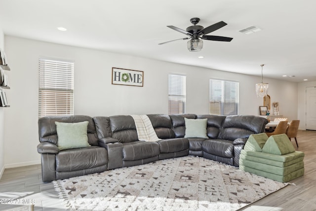 living room with ceiling fan with notable chandelier