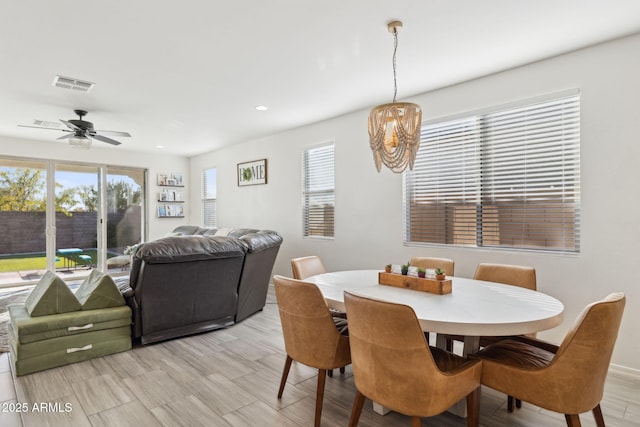 dining room with a wealth of natural light and ceiling fan with notable chandelier