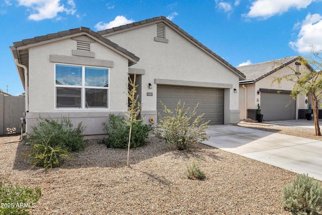 ranch-style home featuring stucco siding, a tiled roof, concrete driveway, and a garage