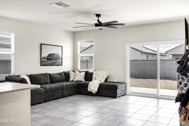 living room featuring light tile patterned floors, visible vents, a healthy amount of sunlight, and a ceiling fan