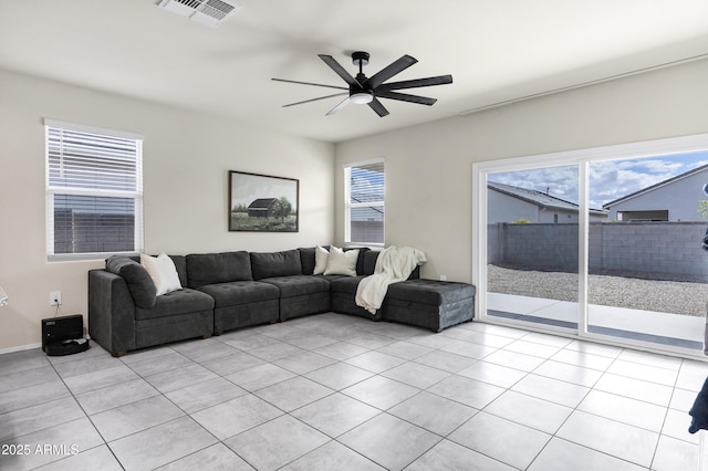 living area with light tile patterned floors, visible vents, a healthy amount of sunlight, and ceiling fan