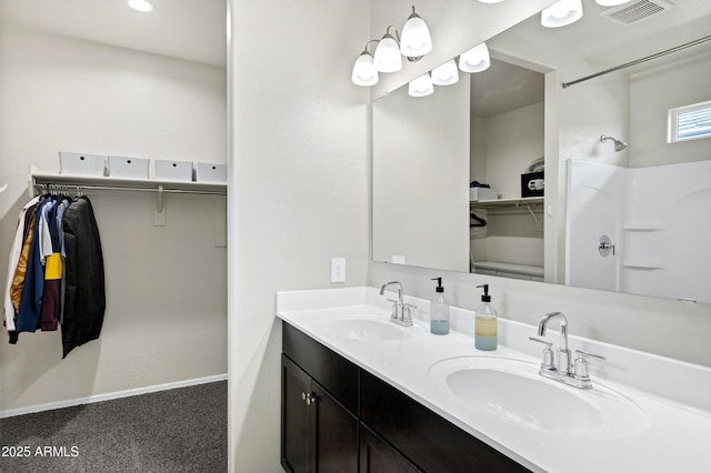 full bath with a sink, visible vents, double vanity, and a spacious closet