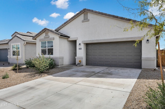 ranch-style house featuring fence, a tile roof, concrete driveway, stucco siding, and an attached garage