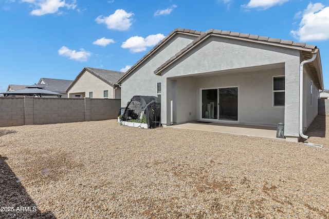 rear view of house with a fenced backyard, stucco siding, a tiled roof, and a patio