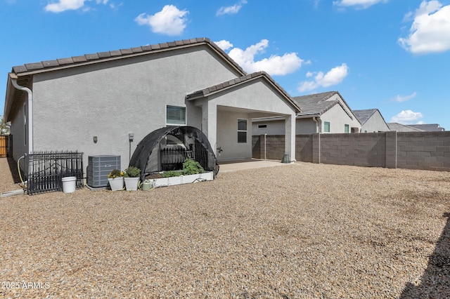 rear view of house featuring fence, central air condition unit, a tiled roof, stucco siding, and a patio area