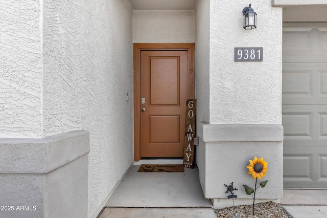 entrance to property featuring a garage and stucco siding